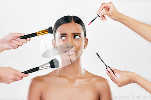 Image of Makeup, brush and confused woman with beauty shine, overwhelmed with beautician on white background. Anxiety with cosmetics, tools and hands crowd female model in studio, cosmetology and skin glow