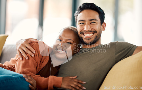 Image of Happy hug, interracial couple and portrait on a sofa at home with love and care in a living room. Woman, young people and together in a house sitting on a lounge couch relax with support and embrace