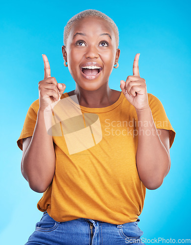 Image of Excited, pointing up and happy black woman with studio advertising space, retail promotion news or announcement. Smile, brand notification and African person gesture at sales deal on blue background