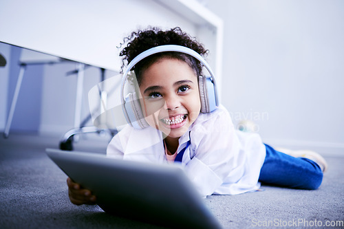 Image of Tablet, headphones and education with a student girl lying on the floor on her home for distance learning. Technology, virtual class and smile with a happy young female pupil watching a school video