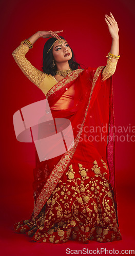 Image of Beauty. dance and Indian woman in a traditional dress, jewellery and religion against a red studio background. Female person, girl and dancer with a cultural outfit, dancing and routine with fashion