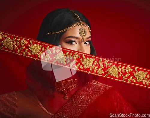 Image of Fashion, culture and portrait of Indian woman with veil in traditional clothes, jewellery and sari. Religion, beauty and eyes of female person on red background with accessory, cosmetics and makeup