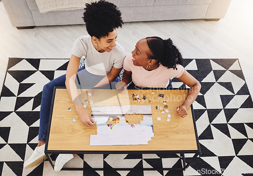 Image of Puzzle, friends together and game in living room for fun, bonding or quality time of playing from above girls in house. Women, jigsaw and people happy to connect pieces on table in family home