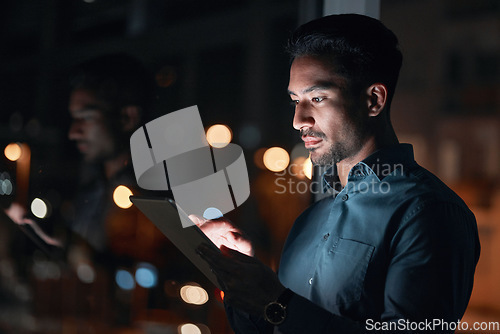 Image of Night, work or man reading on tablet for research, project or planning a proposal in office building, startup or professional employee. Overtime, working or search on internet or online communication