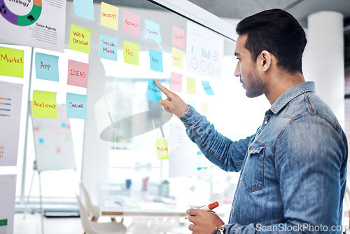 Image of Creative man, sticky note and pointing on glass board for schedule tasks, planning or brainstorming at office. Male person or employee with plan, agenda or marketing strategy for startup at workplace