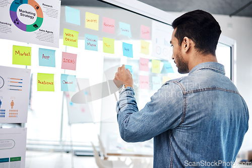 Image of Creative man, sticky note and glass board for schedule tasks, planning or brainstorming at the office. Male person or employee checking plan, agenda or marketing strategy for startup at the workplace