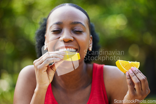 Image of Black woman, vitamin C and eating orange slice for natural nutrition or citrus diet in nature outdoors. Happy African female person enjoying bite of organic fruit for health and wellness in the park