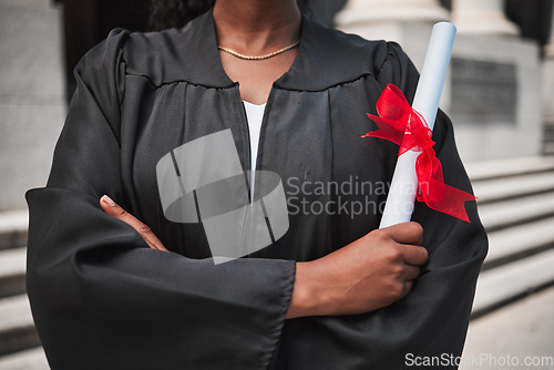 Image of Education, graduation and certificate with a student arms crossed on campus, confident in her achievement. Diploma, university or college with an african graduate standing outdoor at a ceremony