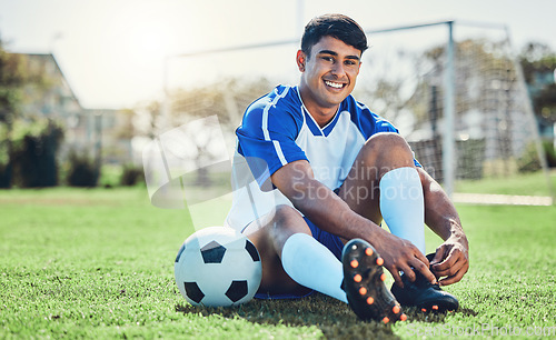 Image of Man, soccer field and tie shoes for sports training, fitness games and performance on stadium ground. Portrait, athlete and happy football player prepare lace sneakers on grass pitch for competition