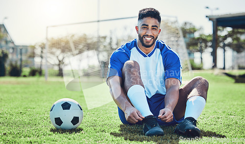 Image of Sports, man or soccer player tie shoes for training, fitness games and performance on stadium field. Portrait, happy indian athlete or lace football sneakers on grass pitch to prepare for competition