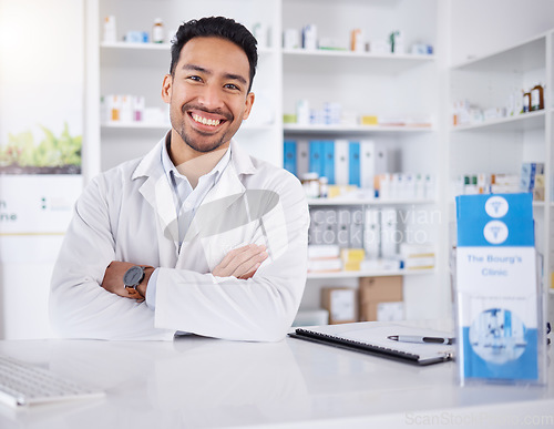 Image of Asian man, portrait and pharmacist with arms crossed in pharmacy, drugstore or shop. Face, confidence or medical professional, happy doctor or worker with a pharmaceutical job for healthcare in Japan