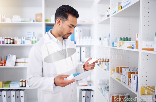 Image of Medicine inspection, pharmacy and man with a note for medical stock or healthcare in store. Retail, work and male Asian pharmacist reading information on a box of pills with a document for inventory