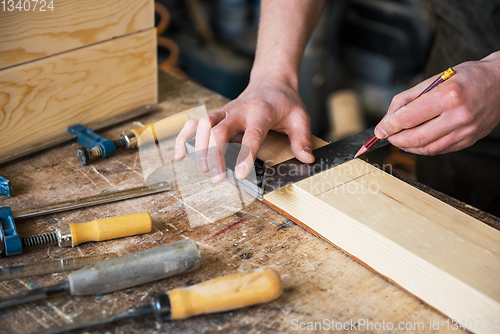 Image of The worker makes measurements of a wooden board