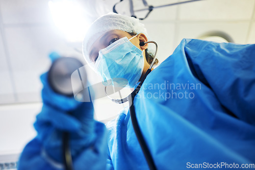 Image of Covid, surgery and a doctor with a light in the theater for a medical procedure or inspection. Hospital, healthcare and portrait of a surgeon or clinic worker with gear for an emergency consultation