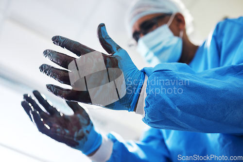 Image of Blood, gloves and operation with a doctor in the hospital emergency room or operating theatre for surgery. Hands, healthcare or medical with a male medicine professional in a clinic for a procedure