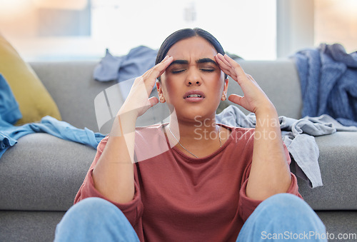 Image of Headache, stress and woman with depression from laundry in a living room, exhausted and unhappy in her home. Anxiety, migraine and female person frustrated with household, task or spring cleaning
