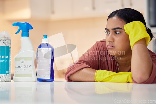 Image of Cleaning, spray bottle and frown with an annoyed woman housekeeper looking at hygiene products in the kitchen. Depression, housekeeping and supplies with a frustrated female cleaner in a home