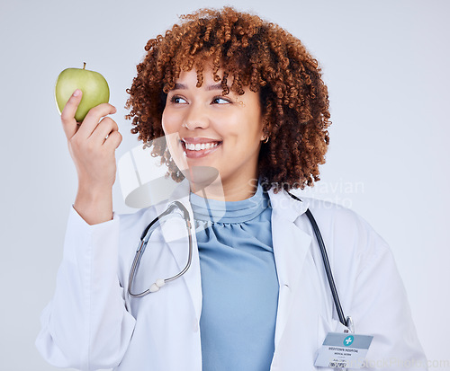 Image of Doctor, happy woman and holding apple in white background, studio and vitamin c wellness. Medical employee, female nutritionist and smile with green fruits for nutrition, healthy food and vegan diet