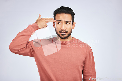 Image of Frustrated, depression and man with gun gesture or stress with mental health or emotion in grey background in studio. Male person, shooting and head with anger or problem with anxiety and fear.