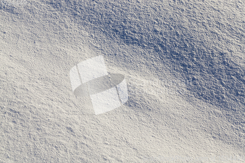 Image of land covered with snow - white snow after snow had fallen and covered the land in the agricultural field. Photo closeup in the winter season, a small depth of field. On visible surface roughness snow