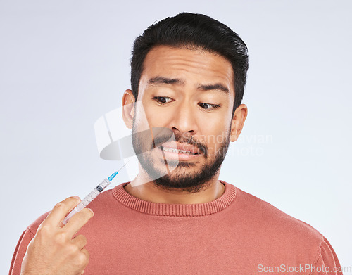 Image of Fear, vaccine and face of asian man in studio with needle, phobia or covid scare on grey background. Corona, compliance and male person afraid of vaccination, medicine or prescription diabetic shot