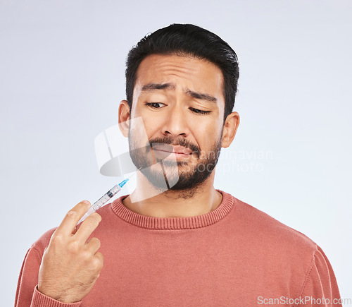 Image of Vaccine, fear and face of asian man in studio with needle, phobia or covid scare on grey background. Corona, compliance and male person afraid of vaccination, medicine or prescription diabetic shot