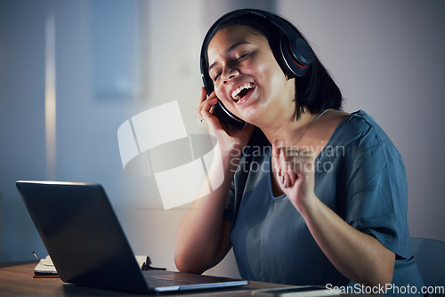 Image of Happy woman, headphones and listening to music at night for online audio streaming on office desk. Female person or employee working late and enjoying sound track or songs on headset at the workplace