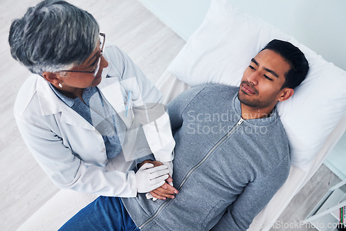 Image of Sick, above and doctor holding hands with a man in a hospital for support, consulting and care. Healthcare, bed and a mature medical person with comfort for a patient with stomach cancer in clinic