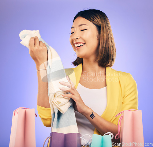 Image of Clothes, shopping bag and happy woman with product sale, discount or promotion on a studio, purple background. Excited young model, asian person or customer fashion choice, retail and e commerce gift