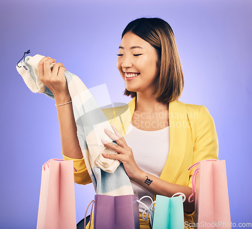 Image of Shopping bag, clothes and woman or customer with product sale, discount or promotion on studio, purple background. Happy young model or asian person with fashion choice, retail and unboxing gift