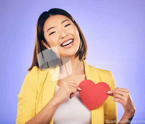 Image of Girl, smile and heart for care in portrait for purple background in studio with asian on valentines day. Support, love and chest with female person with happiness with emoji shape or emotion.