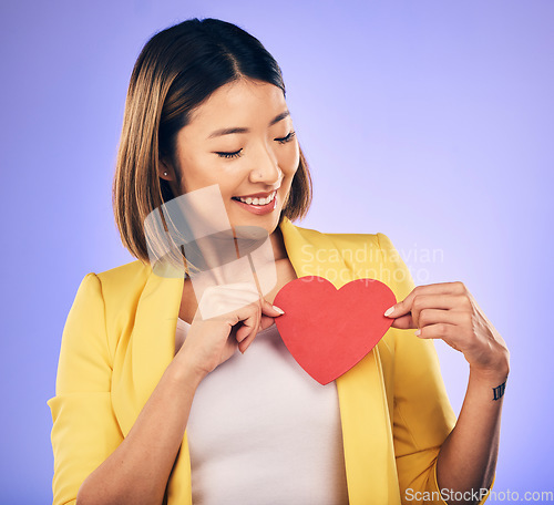 Image of Asian girl, support and paper heart for care with smile in studio with purple background with asian. Peace, wellness and woman with love sign for kindness or hope with happiness and romance emoji.