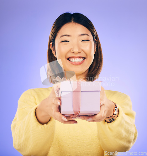 Image of Portrait, smile and Asian woman with a gift, box and celebration against a studio background. Face, happy female person or model with happiness, present and giveaway with a ribbon, surprise and prize