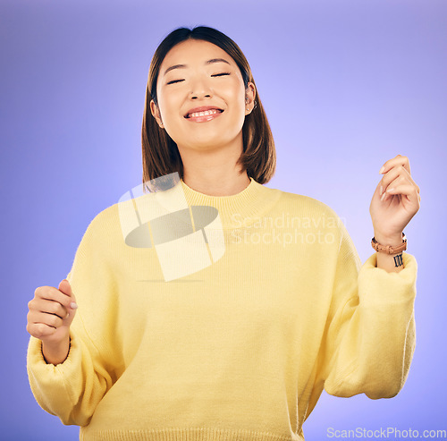 Image of Happy asian woman, dancing and music in freedom or casual fashion against a purple studio background. Female person or model smile enjoying energy, event or party in happiness for clothing style