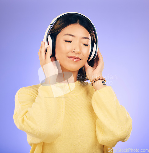 Image of Headphones, music and happy Asian woman relax in studio for streaming app, subscription and radio. Calm, podcast and isolated female person listening to audio, song and track on purple background