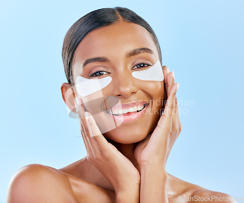 Image of Glow, skincare and portrait of woman with patches for eyes, dark circles and treatment. Smile, face and girl or model with dermatology facial collagen mask isolated on blue background in studio