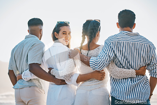 Image of Happy friends, back and hug on beach for holiday, vacation or weekend together in nature. Rear view of group or people standing and bonding in community, support or trust by the ocean coast outside