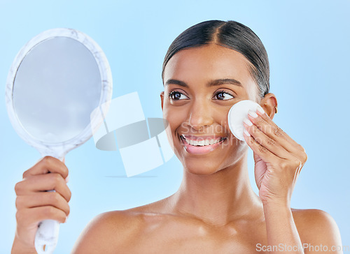 Image of Mirror, cotton and woman with beauty or skincare as cosmetic product treatment isolated in a studio blue background. Cleaning pad, exfoliate and young female person with clean face due to facial