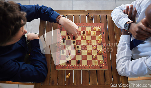 Image of Chess, board game and business men playing at a table from above while moving piece for strategy. Male friends together to play, relax and bond with icon for problem solving, challenge or checkmate