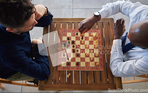 Image of Chess, board game and men playing at a table from above while moving piece for strategy or challenge. Male friends together to play, relax and bond while moving icon for problem solving or checkmate