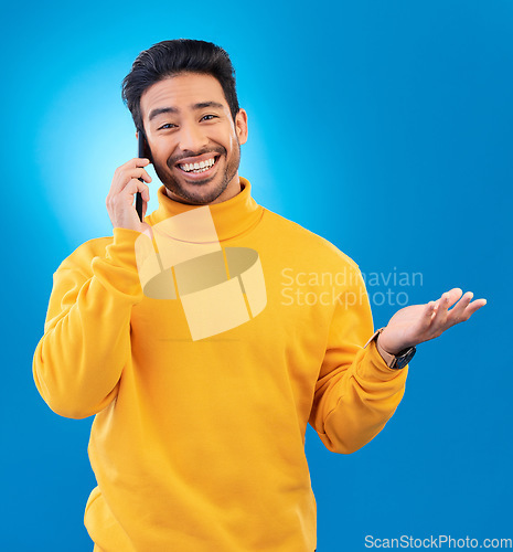 Image of Happy, conversation and portrait of an Asian man on a phone call for communication and networking. Smile, technology and a person speaking on a mobile isolated on a blue background in a studio