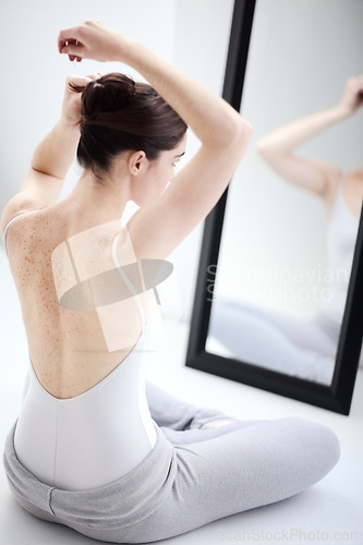 Image of Female ballerina doing her hair by a mirror in a studio before a dance class, performance or concert. Art, creative and back of young ballet dancer getting ready for classical dancing in her room.