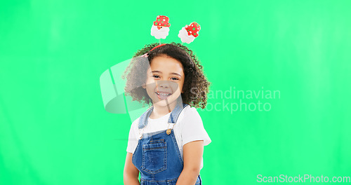 Image of Portrait, children and cute with a girl on a green screen background in studio wearing a funky alice band. Kids, smile and innocent with an adorable little female child standing on chromakey mockup