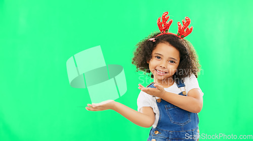 Image of Christmas, green screen and a girl presenting advertising space for product placement in studio. Portrait, kids or celebration with an adorable little child on chromakey mockup for the festive season