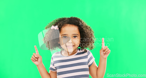 Image of Face smile, girl child and pointing up on green screen in studio isolated on a background. Portrait, emoji and happy kid with hand gesture for mockup, advertising or marketing, branding or chroma key