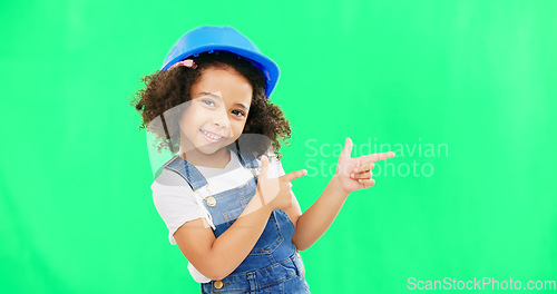 Image of Children, construction and a girl on a green screen background in studio pointing at building space. Kids, architecture and design with a cute female child engineer wearing a hardhat on chromakey