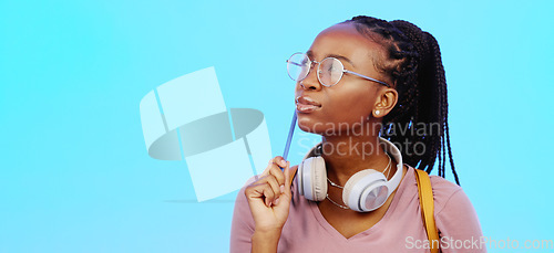 Image of Black woman, thinking and gen z person with student vision and ideas in a studio copy space. Blue background, university students idea and headphones of a young female with glasses contemplating with