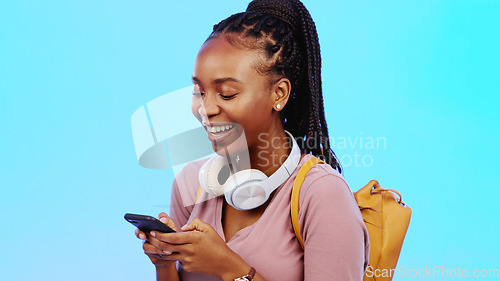 Image of Phone, happy and black woman in a studio networking on social media, mobile app and the internet. Happiness, laugh and African female model typing a text message on a cellphone by a blue background.