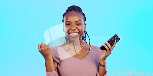 Image of Wow, happy and excited black woman with phone receiving email news of bonus, promotion or announcement in studio. Winning, prize notification and African girl celebrating with smile on blue backgrou