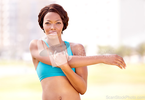 Image of Fitness, portrait and black woman stretching arm outdoor for running, training body and workout. Face, serious mindset and arm stretch by African athlete lady runner in a park for warm up or run